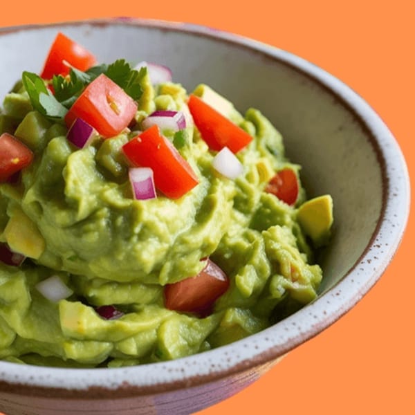 A bowl of Taza Modern Mexican guacamole, topped with diced tomatoes, red onions, and cilantro.