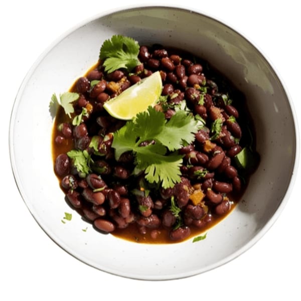 Taza Modern Mexican's black beans in a white bowl, garnished with cilantro and a lime wedge.