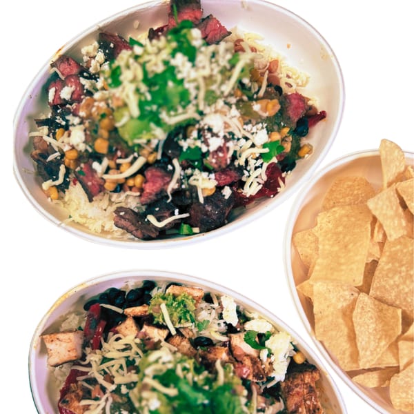 Two Taza Modern Mexican bowls, one with steak and one with chicken, alongside a bowl of tortilla chips.